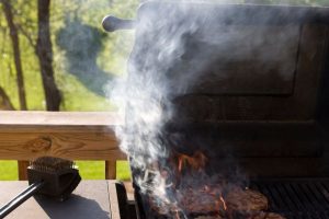 Backyard gas grills with food and smoke; grilling mistakes that can lead to serious injury.