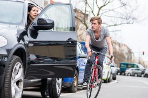 Road safety tips for cyclists; women opening car door in front of man on bicycle